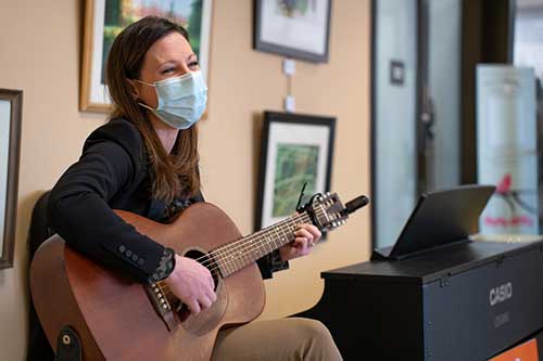 Music therapy: Young woman playing a guitar